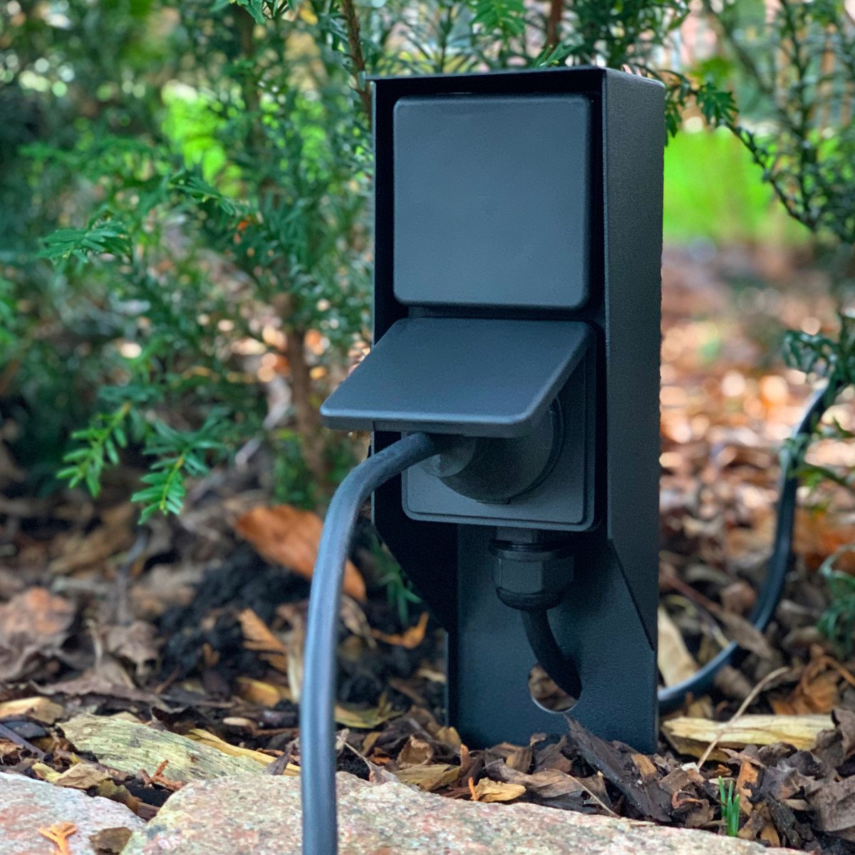 Prise extérieure noire avec piquet pratique et deux points de courant pour éclairage de jardin.